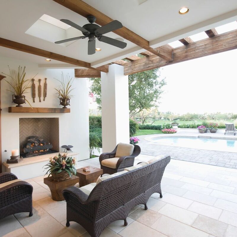 Elegant outdoor patio with comfortable seating and a fireplace overlooking a pool.
